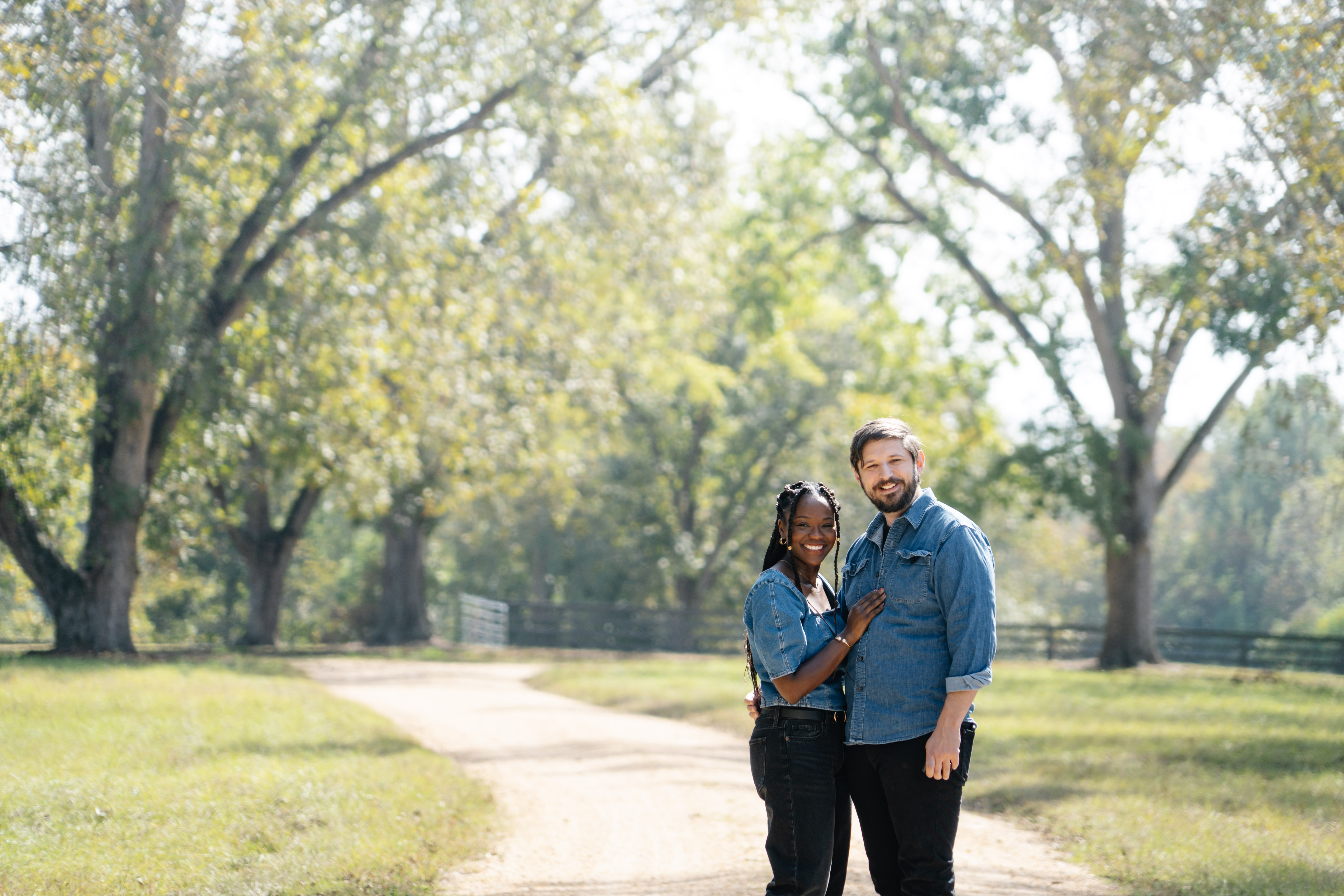 a couple standing side by side in front of a beautiful field