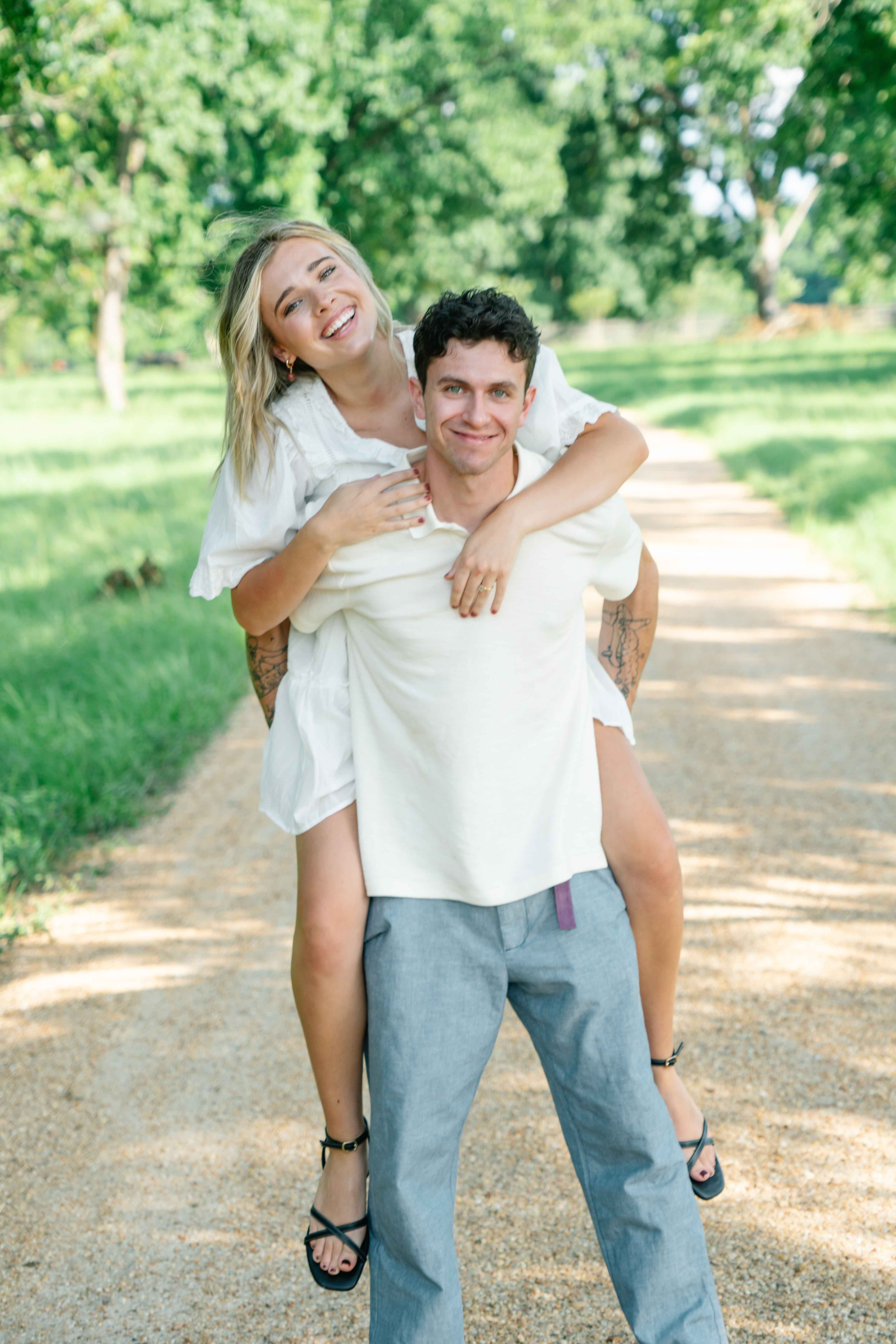 a couple standing side by side in front of a beautiful field