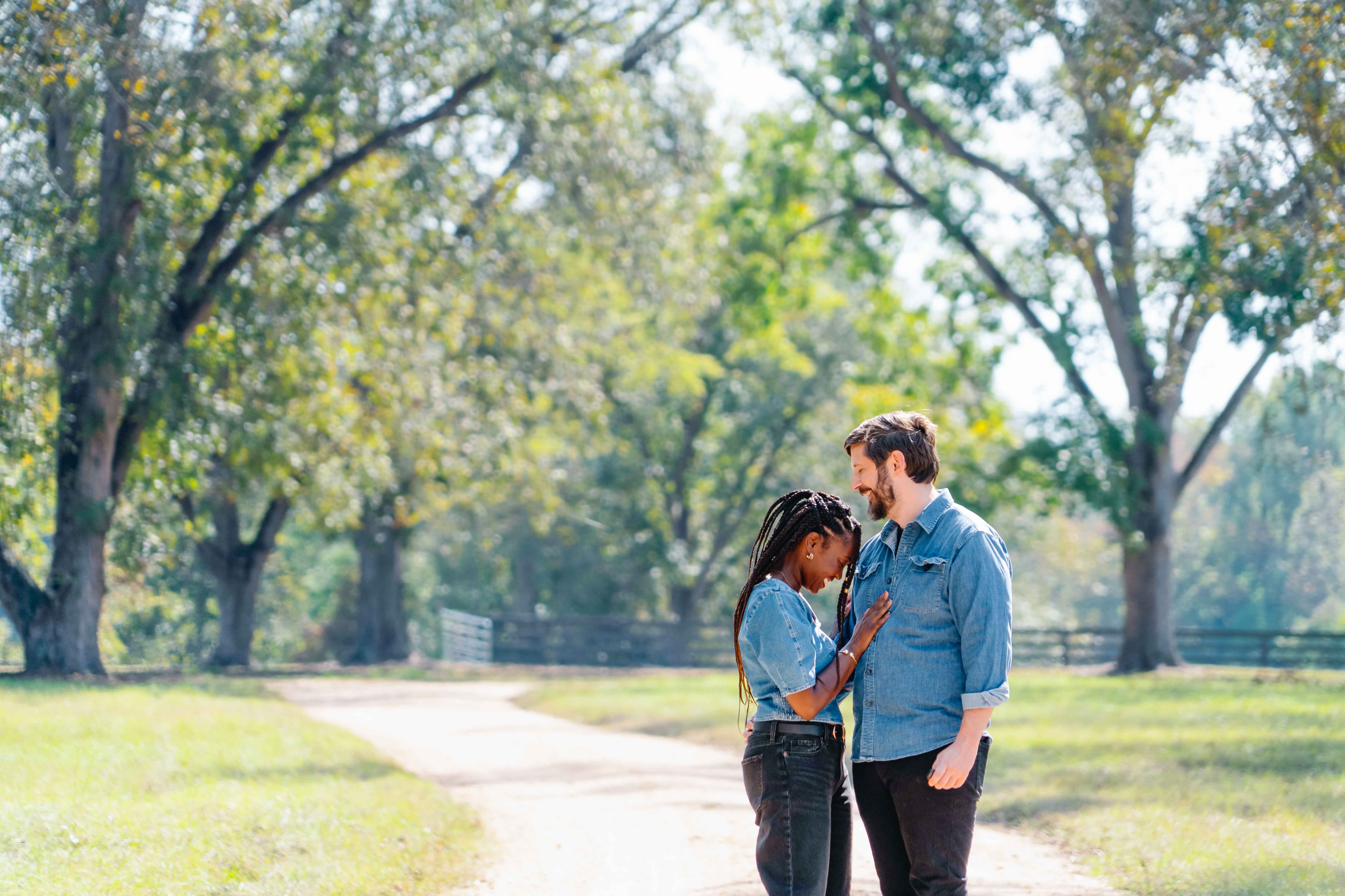 a couple standing side by side in front of a beautiful field